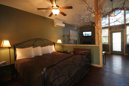 Cozy bedroom with a king-size bed, ceiling fan, and large windows, featuring warm lighting and rustic decor.