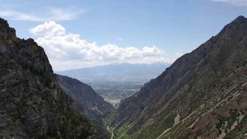 A panoramic view of a valley surrounded by steep mountains under a partly cloudy sky.