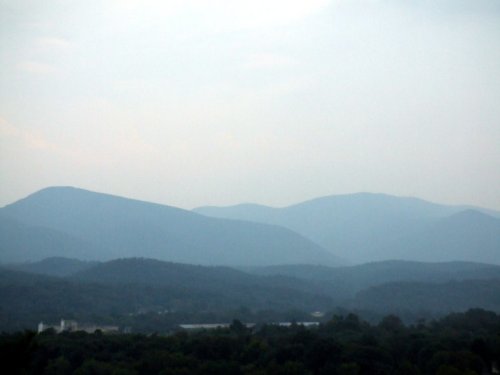 A hazy landscape of rolling mountains under a soft, overcast sky.