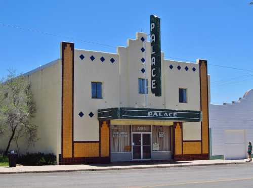 Art Deco-style building with "Palace" sign, featuring colorful tile accents and large windows. Bright blue sky above.