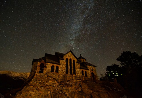 A stone church silhouetted against a starry night sky, with the Milky Way visible above.