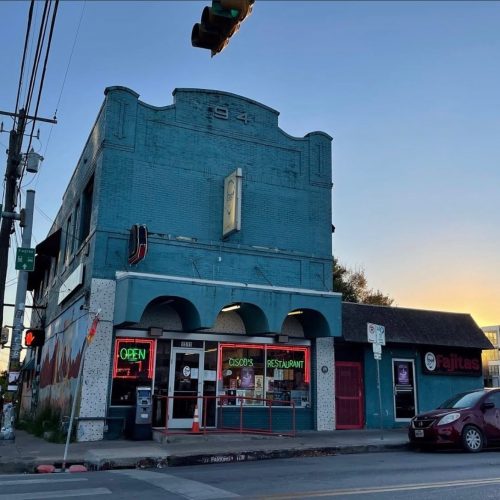 A blue brick building with a clock, featuring "Cisco's Restaurant" and "Fajitas" signs, at dusk.