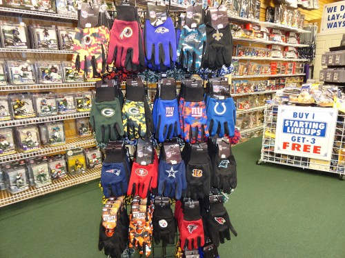 A display of colorful sports gloves featuring various NFL team logos in a retail store.