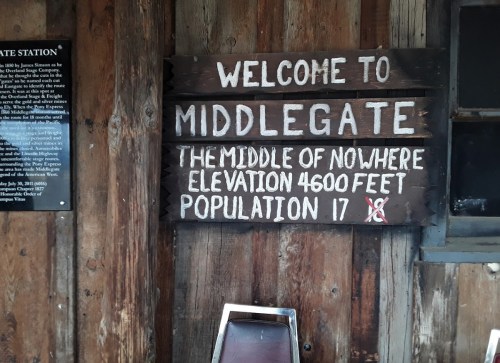 Wooden sign reading "Welcome to Middlegate: The middle of nowhere, elevation 4600 feet, population 17."