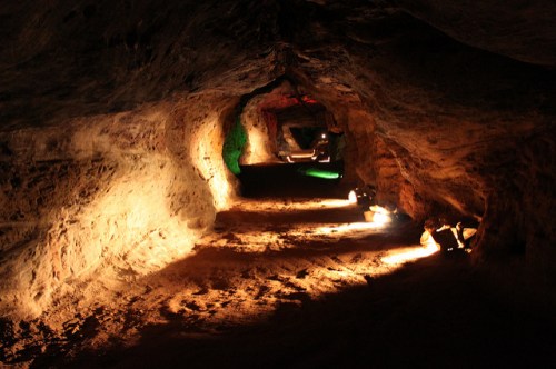 A dimly lit cave tunnel with textured walls and soft lighting illuminating the path ahead.