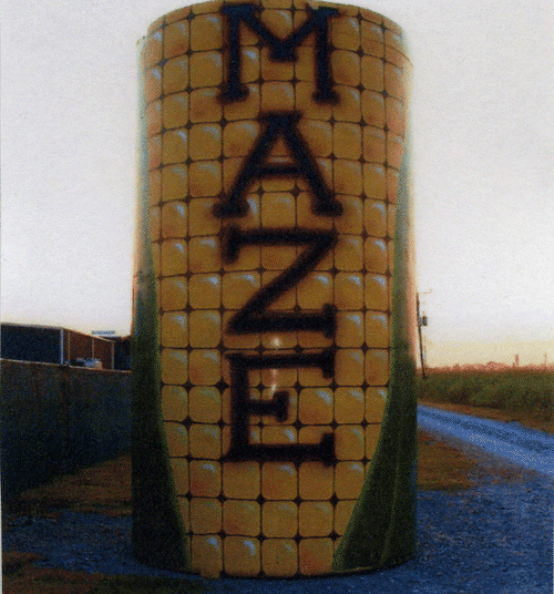 A large cylindrical structure painted to resemble corn, with the word "MAZE" prominently displayed.