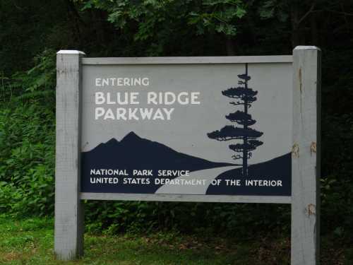 Sign marking the entrance to Blue Ridge Parkway, featuring mountains and trees, with National Park Service branding.