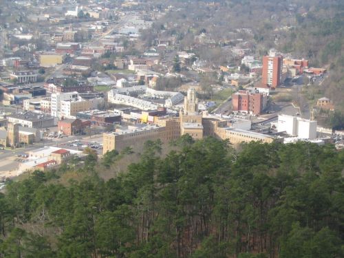 Aerial view of a small town with buildings, trees, and a distant landscape.