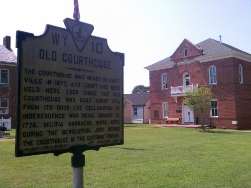 Historic sign in front of a red brick courthouse, detailing its history and significance in Eastville, WY.