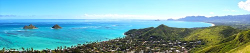 A panoramic view of a vibrant blue ocean, green hills, and a coastal town under a clear sky.