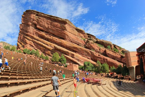 A wide view of Red Rocks Amphitheatre, showcasing its iconic rock formations and empty seating under a blue sky.
