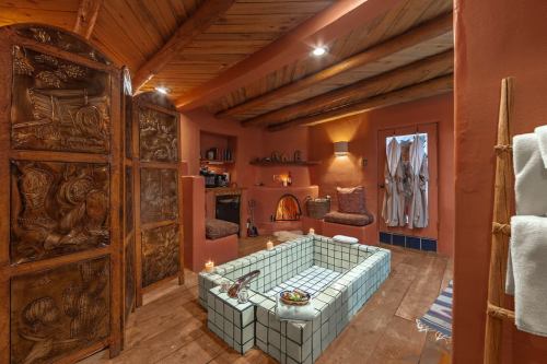 A cozy spa room with wooden beams, a tiled soaking tub, candles, and plush seating, creating a relaxing atmosphere.