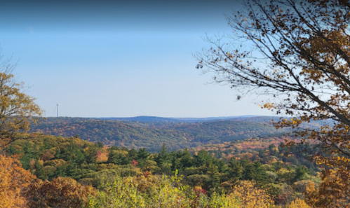 A scenic view of rolling hills covered in autumn foliage under a clear blue sky.