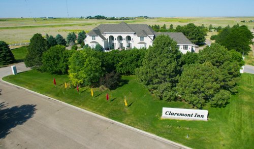Aerial view of Claremont Inn surrounded by greenery and colorful flags, set against a clear blue sky.