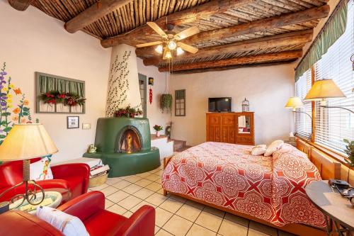 Cozy bedroom with a red patterned bedspread, rustic wooden beams, a fireplace, and comfortable seating.