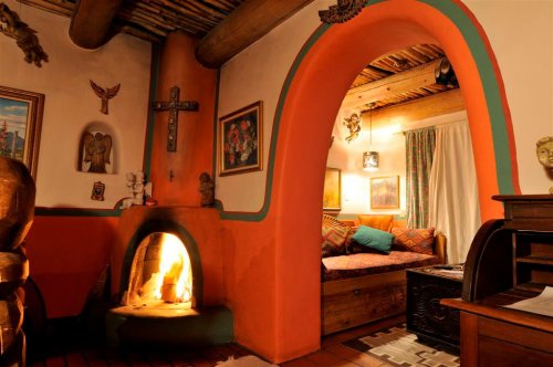 Cozy interior featuring a colorful archway, a fireplace, and a seating area with artwork and decorative elements.