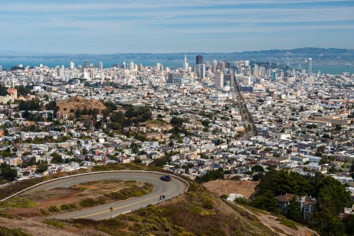 A panoramic view of San Francisco, showcasing the city skyline and winding roads from a hillside perspective.