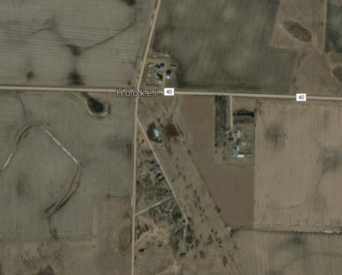 Aerial view of a rural area with fields and roads, featuring the town of Hooker and nearby structures.