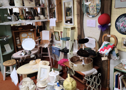 A cozy antique shop filled with various vintage items, including furniture, dishes, and decorative pieces.