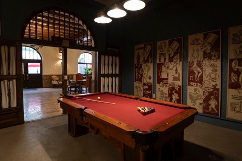 A cozy room featuring a billiard table with a full set of balls, surrounded by vintage decor and warm lighting.