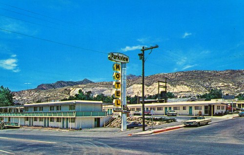 A vintage postcard of Parkview Motel, featuring a sign, two buildings, and a mountainous backdrop under a clear blue sky.