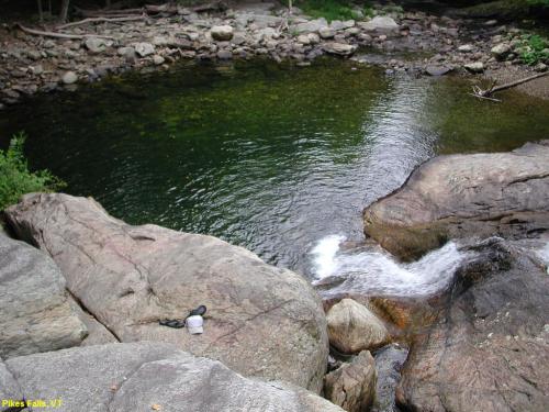 A serene view of Pike's Falls, featuring smooth rocks and a calm pool of water with a gentle waterfall.