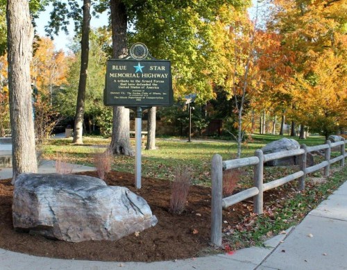 Sign for Blue Star Memorial Highway surrounded by trees and rocks, honoring military veterans.
