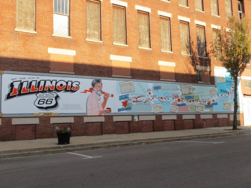 A mural promoting Route 66 in Illinois, featuring colorful graphics and a vintage-style illustration of a man.