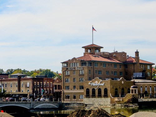 Historic Hotel Baker with an American flag, overlooking a river and nearby buildings on a clear day.