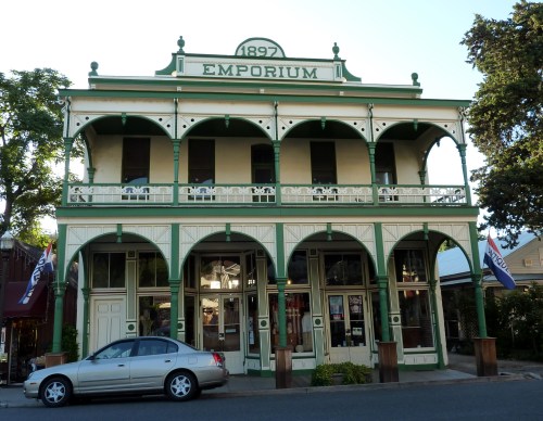Historic two-story emporium building with green trim, arched balconies, and a sign reading "1897 Emporium."