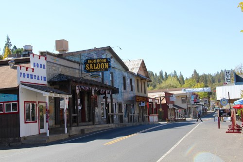 A quiet street scene featuring historic buildings, including the Iron Door Saloon, under a clear blue sky.