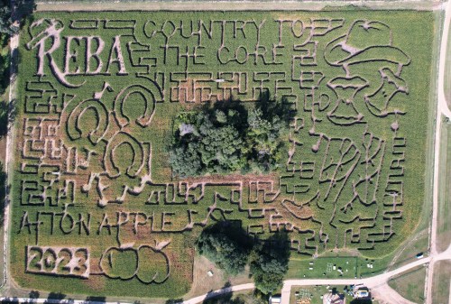 Aerial view of a corn maze featuring the text "REBA COUNTRY TO THE CORE" and apple designs, labeled 2023.