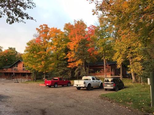 A scenic view of a parking area with colorful autumn trees and a rustic building in the background.