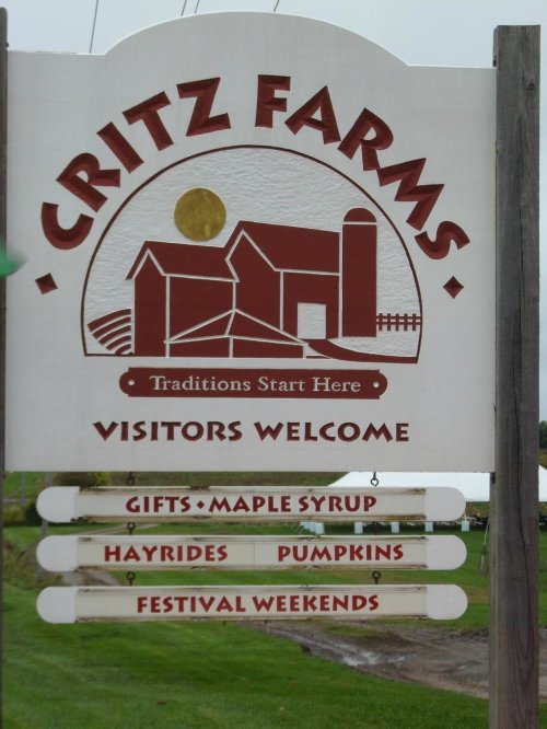 Sign for Critz Farms, welcoming visitors with offerings like gifts, maple syrup, hayrides, pumpkins, and festival weekends.
