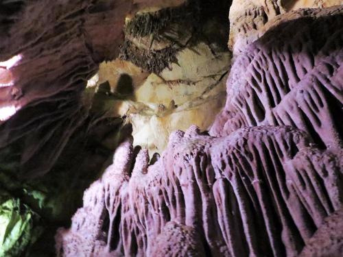 A colorful cave interior with unique rock formations and shadows, showcasing textures and natural patterns.