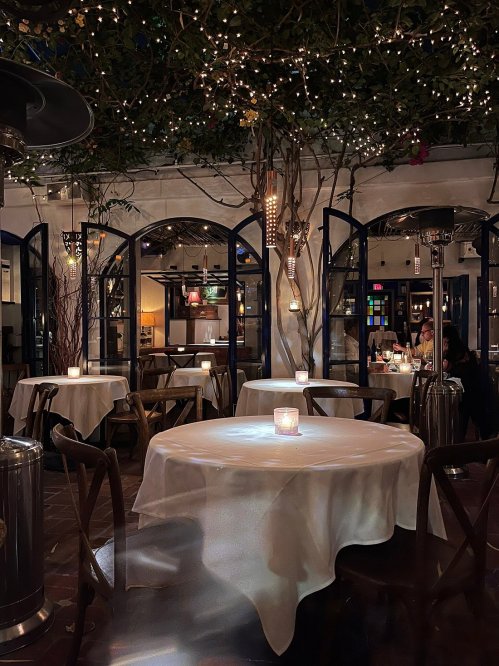 Cozy restaurant interior with dim lighting, candlelit tables, and decorative string lights.