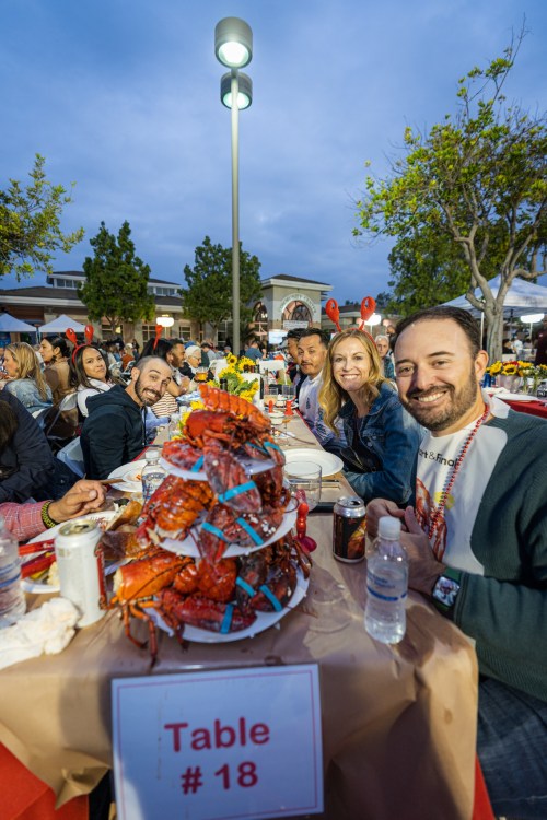 A group of friends enjoying a seafood feast at a table with a large pile of crawfish and drinks.