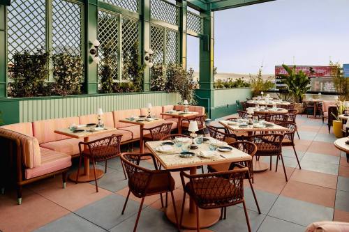 A stylish restaurant patio with colorful seating, tables set for dining, and greenery in a bright, airy atmosphere.