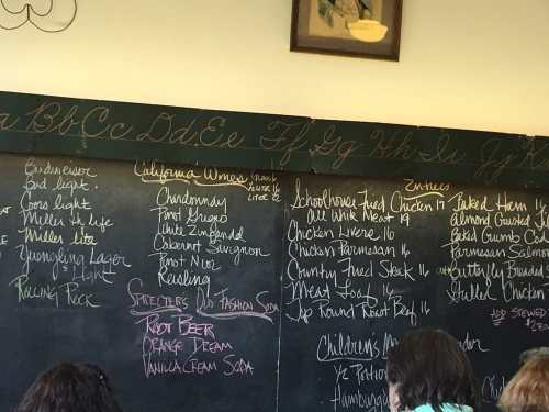 A chalkboard menu featuring drinks, food items, and children's options in a casual dining setting.