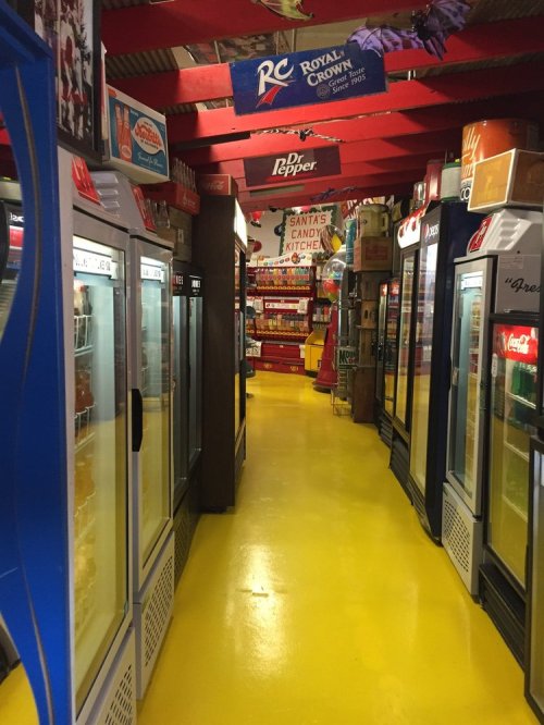 A colorful aisle lined with vending machines and coolers, featuring bright yellow flooring and various snack displays.