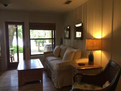 Cozy living room with a sofa, wooden coffee table, lamp, and large windows overlooking a scenic outdoor view.