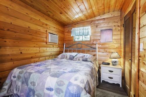 Cozy wooden bedroom with a double bed, nightstand, lamp, and window, featuring warm tones and a quilted blanket.