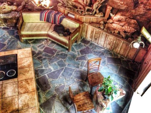 Cozy interior with a stone floor, wooden walls, a sofa with a blanket, and a small table with a plant.