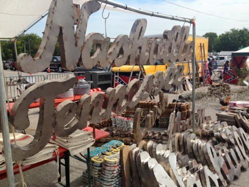 A weathered sign reading "Nashville Tennessee" displayed at an outdoor market, surrounded by various handmade items.