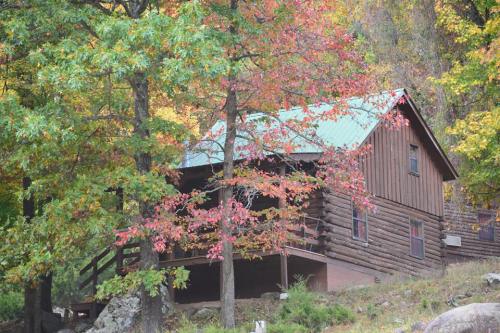 A rustic log cabin surrounded by colorful autumn trees and foliage.