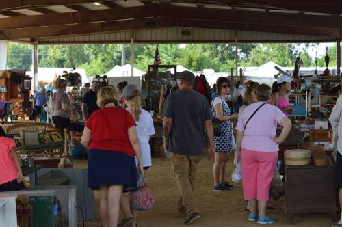 A bustling market scene with people browsing various stalls under a large covered area.