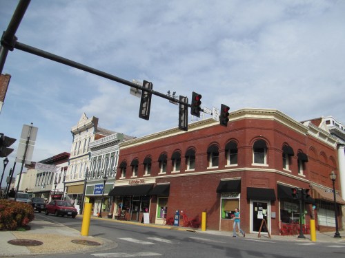 A street view of a historic downtown area with brick buildings, traffic lights, and a cloudy sky.