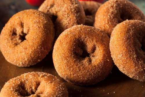 A close-up of freshly baked cinnamon sugar donuts arranged on a wooden surface.