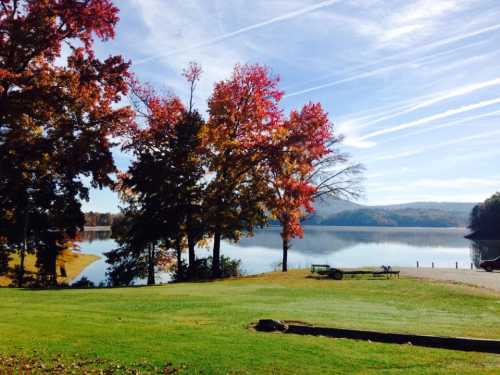 A serene lake surrounded by colorful autumn trees and a clear blue sky, reflecting the vibrant foliage.