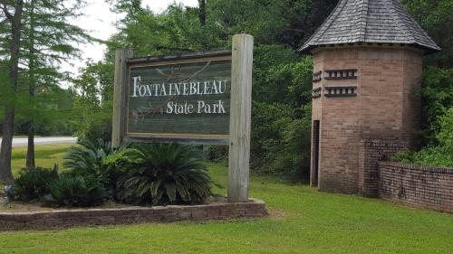Sign for Fontainebleau State Park, featuring greenery and a brick tower in a natural setting.